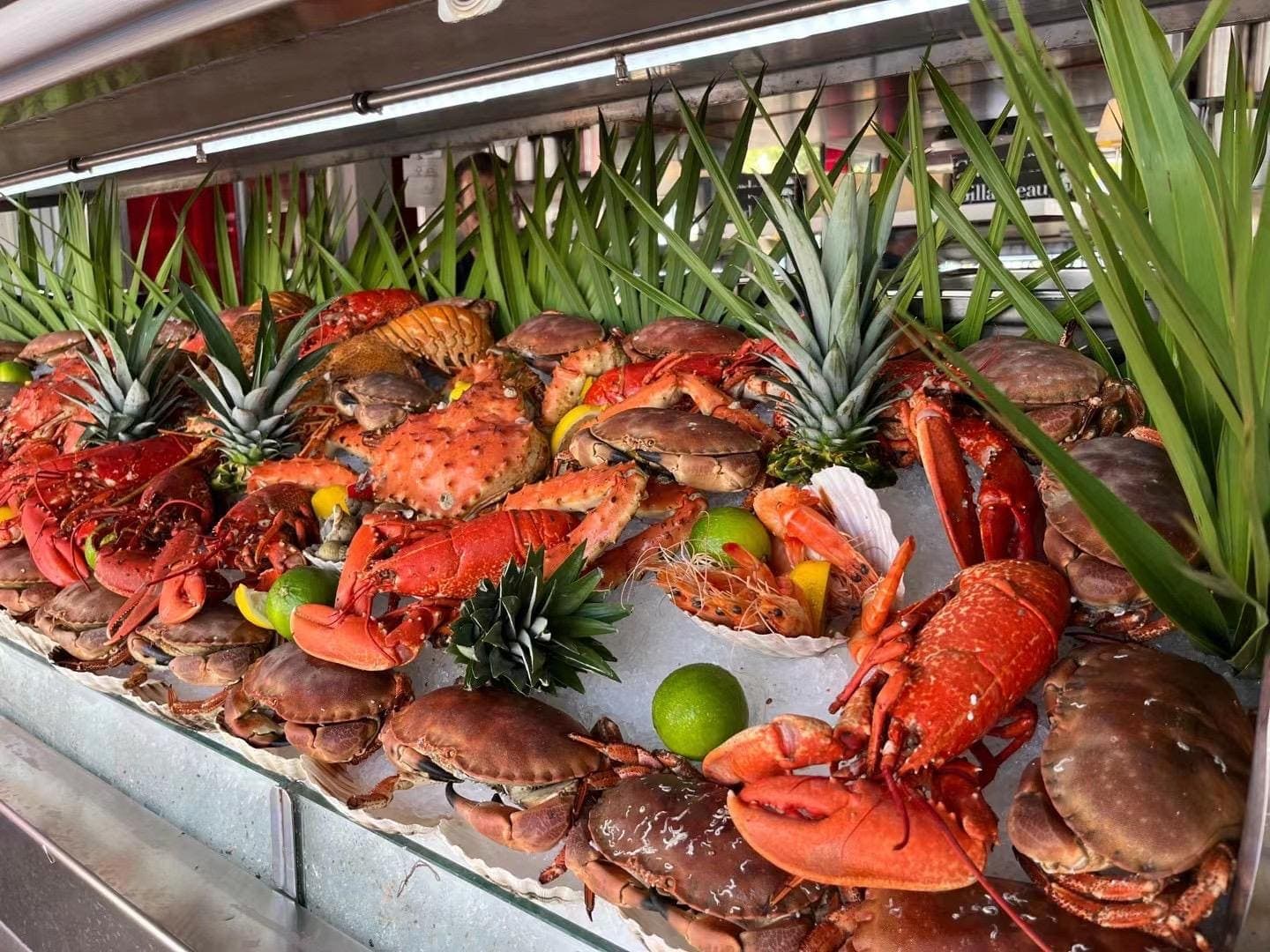 Plateau de fruits de mer sur glace : tourteaux, langoustines et homards décorés d’agrumes et d’ananas