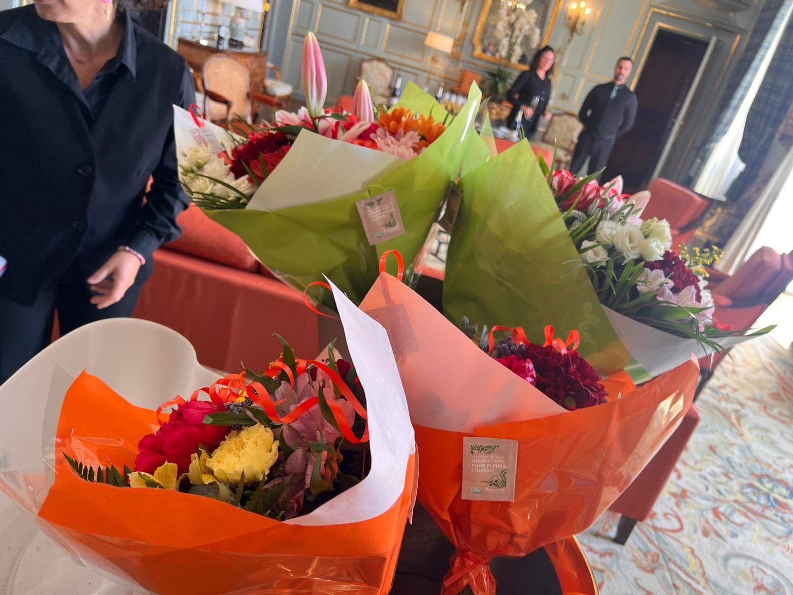 Convives tenant des bouquets de fleurs dans un salon aux dorures, lors d’une réception
