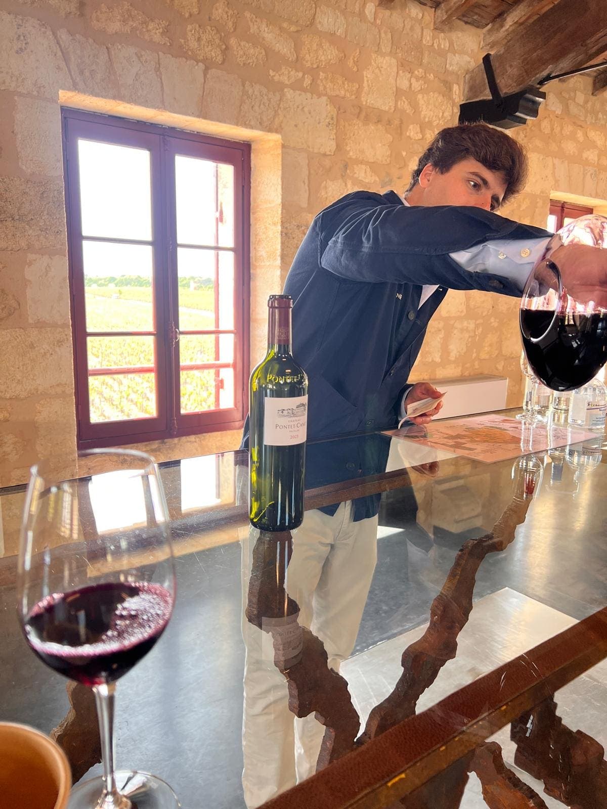 Décantation d’un Château Pontet-Canet dans un chai en pierre avec vue sur les vignes